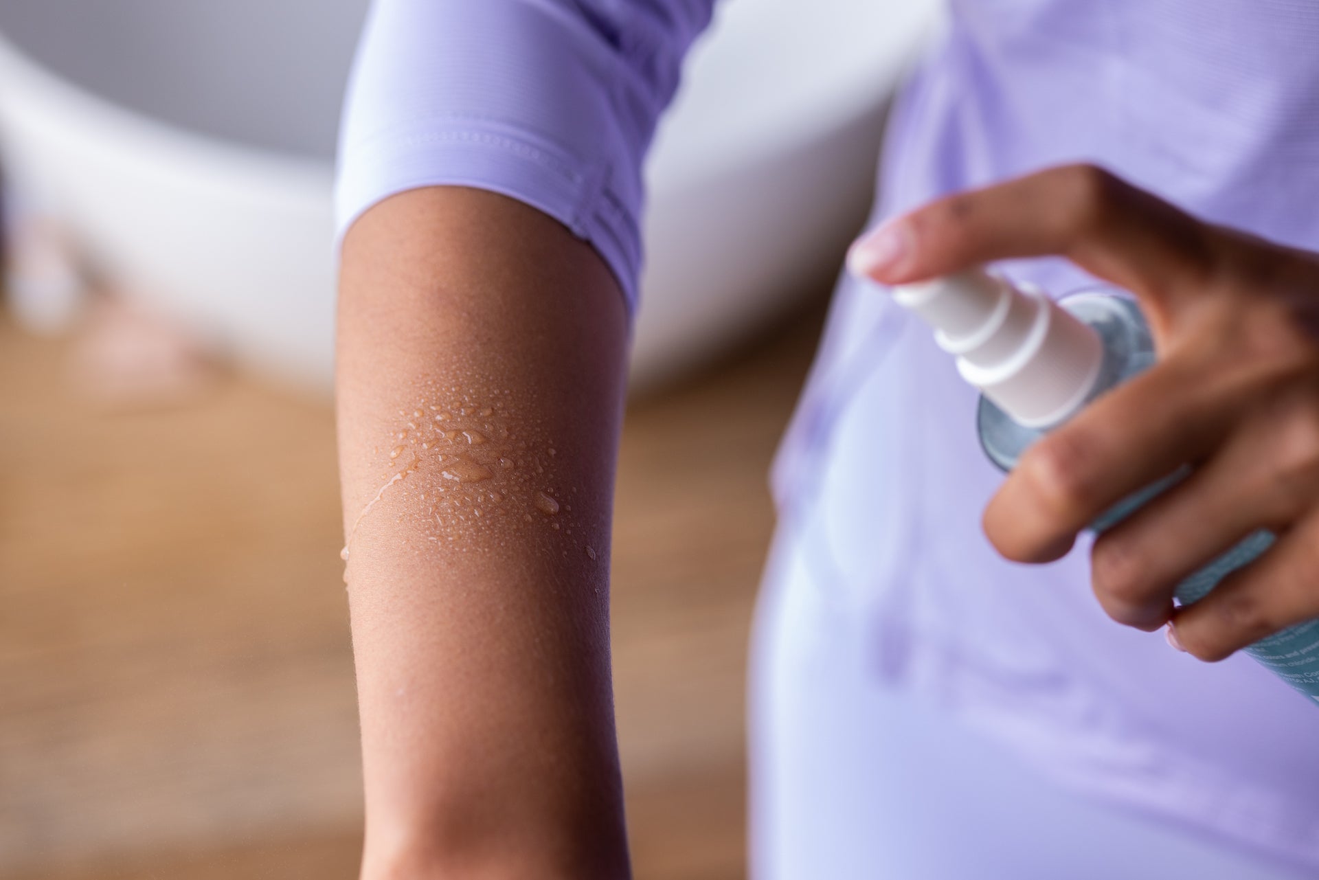 Woman spraying origin magnesium oil on arm